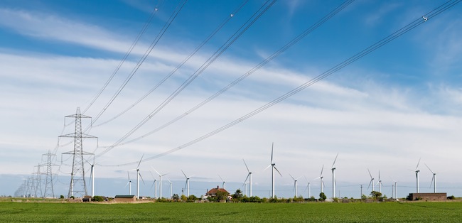 Power lines and wind turbines in East Sussex, UK. Wikipedia Commons Photo by DAVID ILIFF [License: CC-BY-SA 3.0]